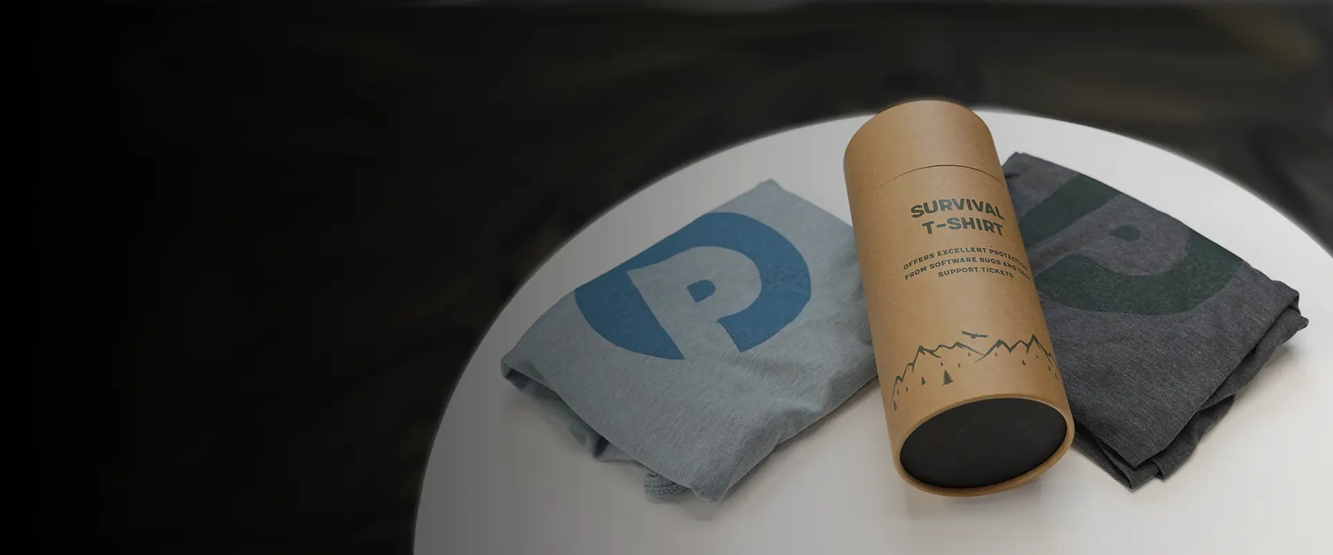 Two Product Perfect T-shirts on a table with the Survival Tube on top of them